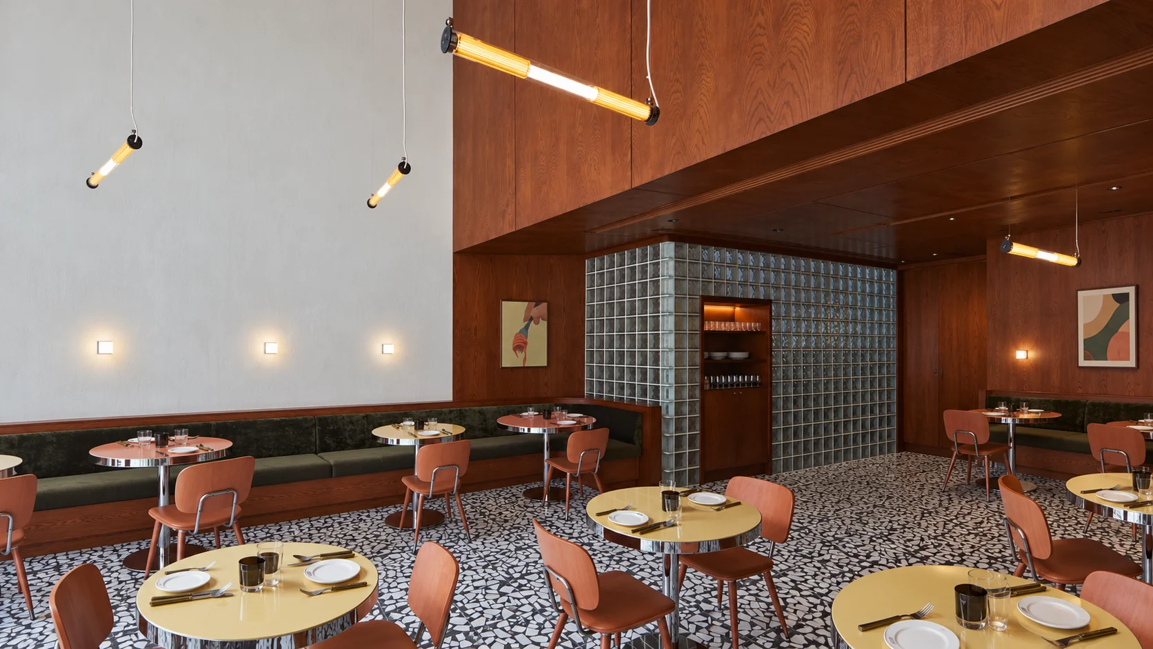 Warm wood paneling, olive banquettes, and round tables in the Neal and Bella dining room